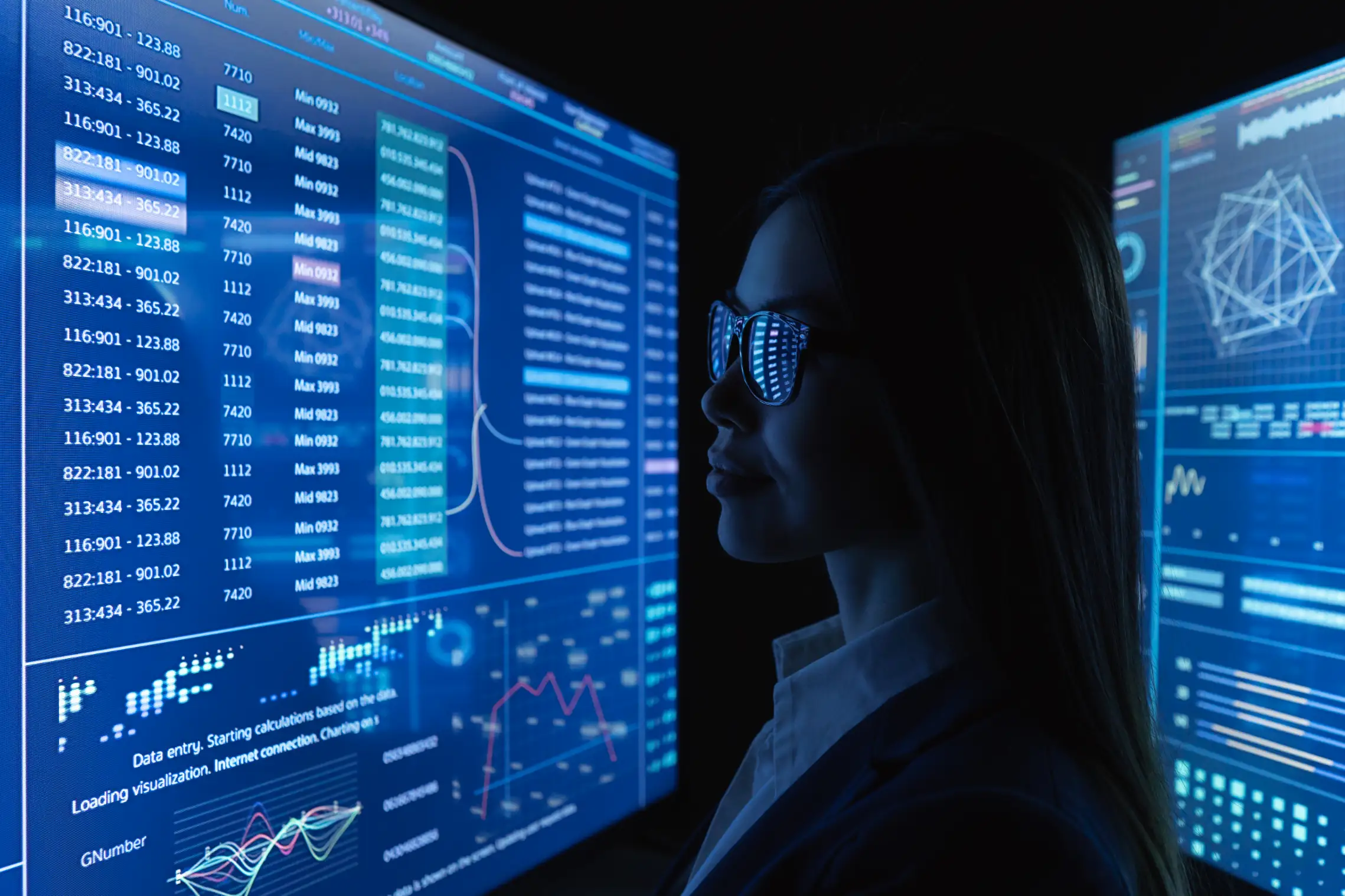 woman analyzing data on multiple computer screens